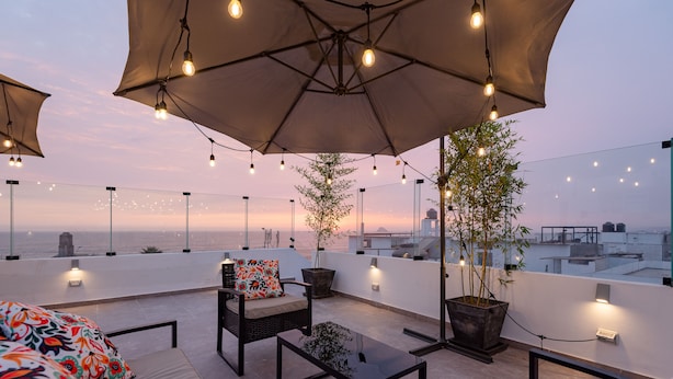 A rooftop terrace with outdoor seating, umbrellas, string lights, and potted plants. - Departamento En La Playa De Estreno Con Piscina (Punta Hermosa)