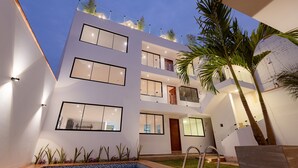 A modern multi-story building with a pool, balconies, and outdoor plants. - Departamento En La Playa De Estreno Con Piscina (Punta Hermosa)