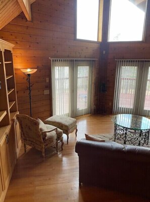A cozy room with wooden walls, a glass table, a sofa, and a chair.
