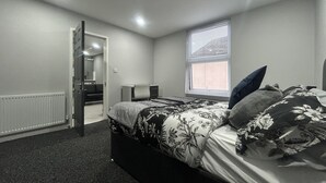 A bedroom with a bed, a desk, a chair, a radiator, and a window with blinds. - Private Luxury Apartment - Free Parking & Wi-fi (Coventry)