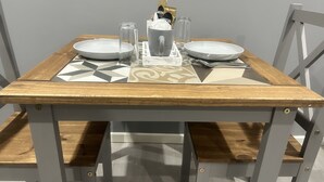 A dining table with a geometric-patterned tablecloth, two white plates, a clear glass, a coffee cup, and a napkin dispenser. - Private Luxury Apartment - Free Parking & Wi-fi (Coventry)