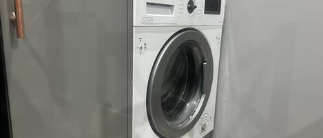 A front-loading washing machine with a control panel, a door handle, and a label indicating it is a 'Laundry Room'.