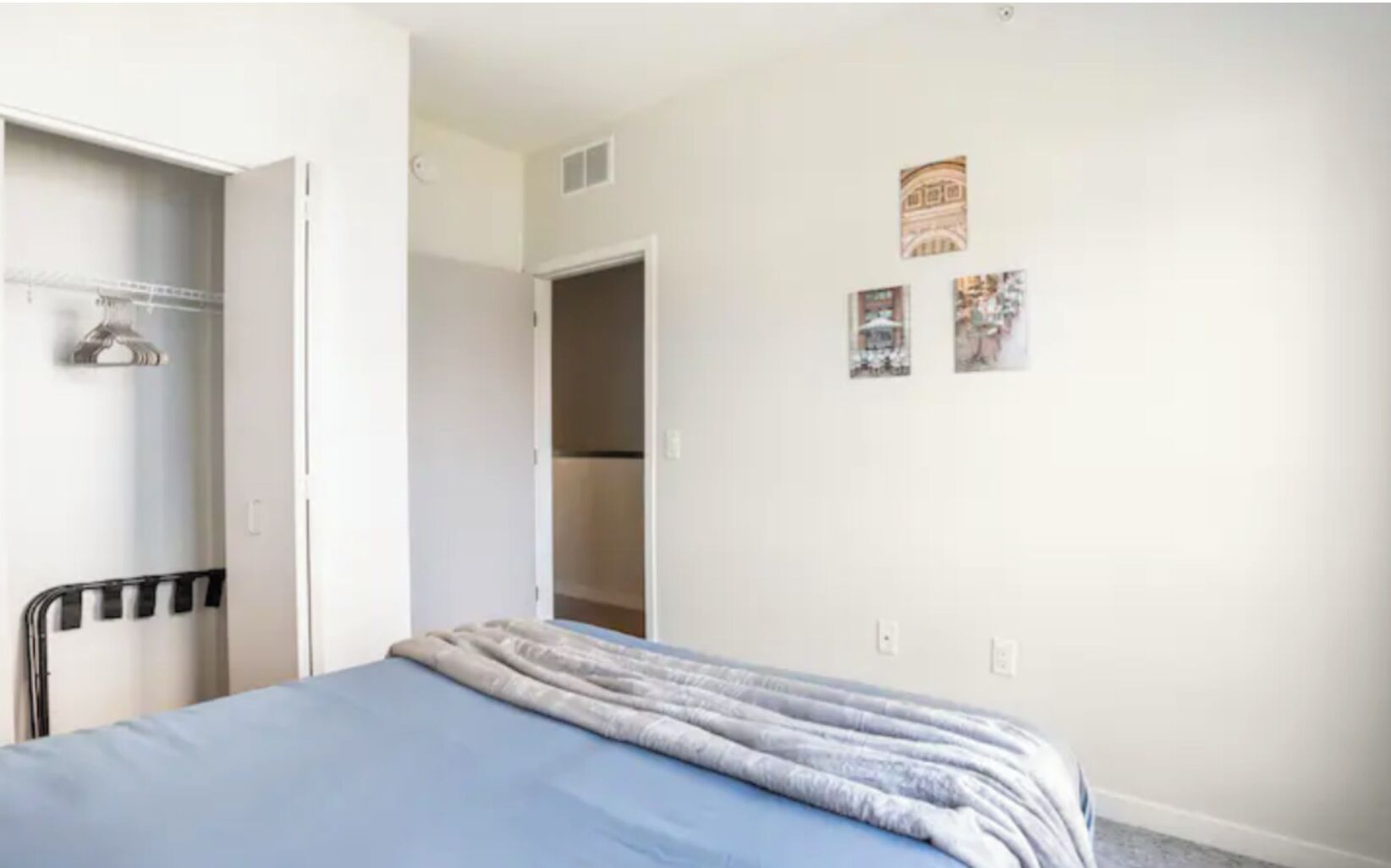 A bedroom with a bed, a wardrobe, and a door leading to a bathroom.