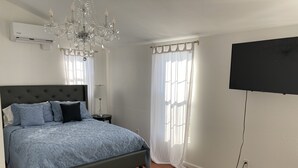 Ein Schlafzimmer mit einem Bett, einer Chandelieber, einem Flachbildfernseher und einem Teppich.