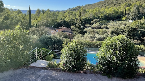 A pool surrounded by lush greenery and a hillside. - Villa Provençale Avec Piscine (Le Cannet-des-Maures)