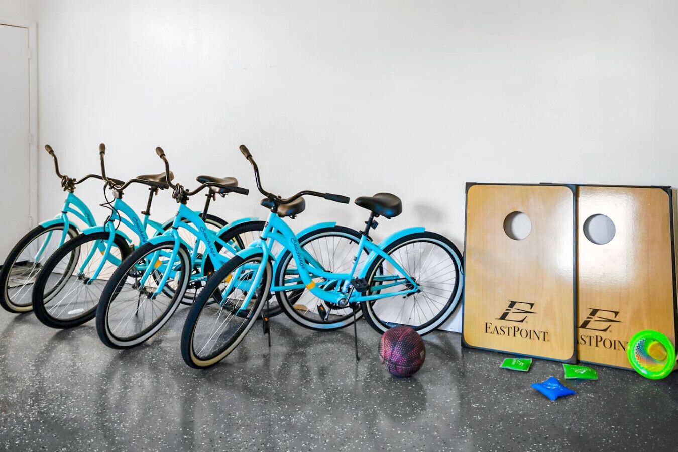 A row of turquoise bicycles parked against a wall, with a large wooden box labeled "EASTPOINT" beside them.