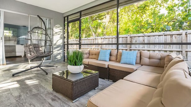 A modern outdoor living space with a sofa, a hanging chair, and a coffee table.