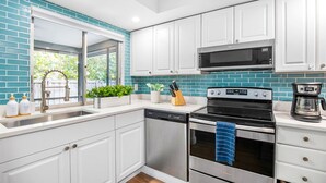 A modern kitchen with white cabinets, a black stove, and a microwave.