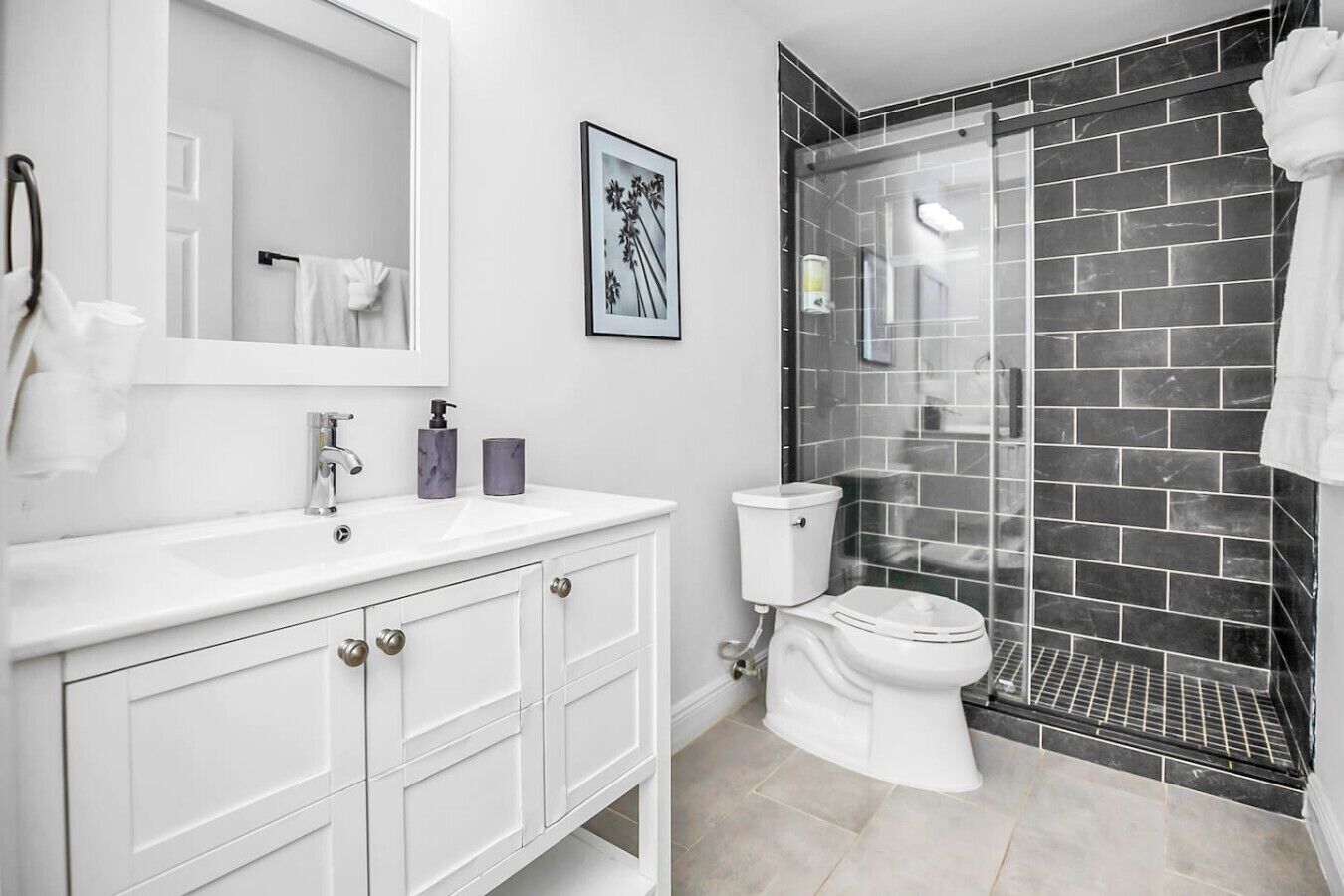 A modern bathroom with a white vanity, a glass shower enclosure, and a toilet.