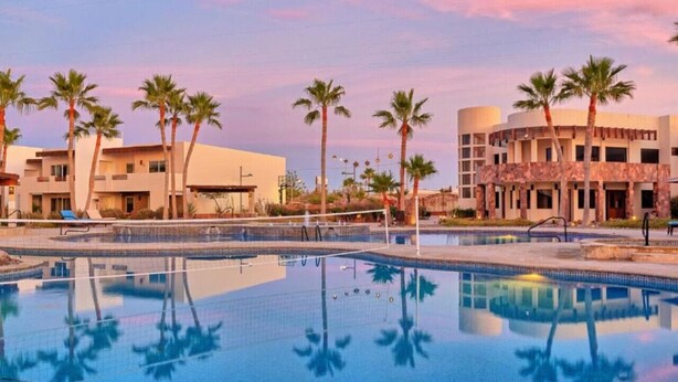 A swimming pool with palm trees and buildings in the background.