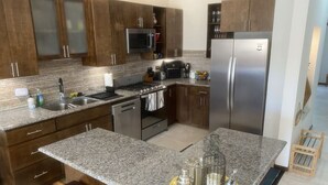 A modern kitchen with granite countertops, stainless steel appliances, and wooden cabinets.
