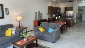 A modern living room with a gray sofa, a coffee table with a plant, and a dining area with a table and chairs.