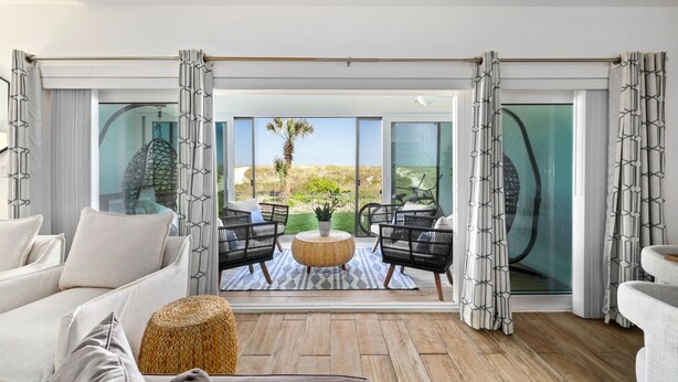 A modern living room with a large sliding glass door leading to a balcony with a view of the desert. - Oceanfront Condo:1st Floor, Steps to the Ocean (Jacksonville Beach)