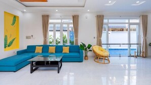 Una sala de estar moderna con un sofá seccional azul, una mesa de centro de vidrio y una mecedora amarilla.