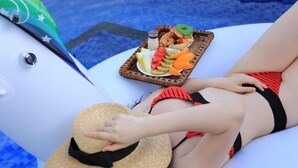 Eine Person entspannt am Pool, mit einem Tablett Essen und einem Strohhut.