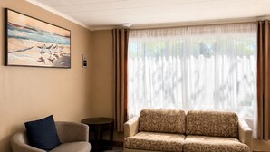 Una sala de estar con un sofá, una silla, una mesita y un cuadro en la pared.