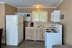 A compact kitchen with a refrigerator, microwave, stove, and sink.