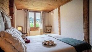 Een houten kamer met een bed, een raam, een stoel en een dienblad met gebak.