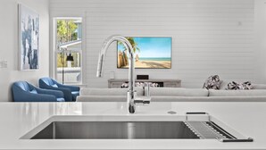 A modern kitchen with a stainless steel sink, a built-in oven, and a large window overlooking a beach. - Vacation Station with Private Pool and Low-Speed Vehicle (Miramar Beach)