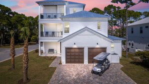 A two-story house with a garage, a balcony, and a covered patio. - Vacation Station with Private Pool and Low-Speed Vehicle (Miramar Beach)