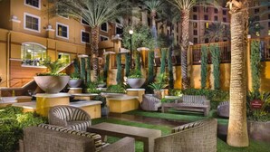 An indoor courtyard with wicker furniture, palm trees, and a 'No Smoking' sign. - Resort near airport, convention center & casinos. (Las Vegas)