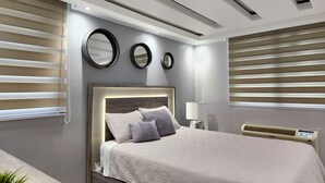 Quarto moderno com uma cama grande, três espelhos na parede e um ar condicionado instalado.