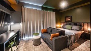 Un dormitorio moderno con cama, sofá, escritorio y televisor.