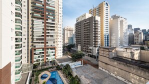 Un edificio residencial alto con varios balcones, una piscina en la azotea y edificios altos circundantes.