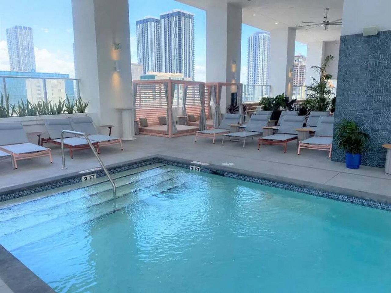 A rooftop pool with lounge chairs and a city view.