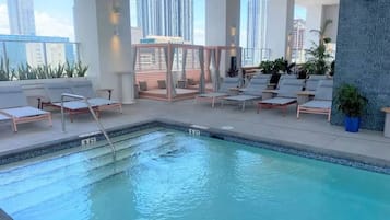 A rooftop pool with lounge chairs and a city view.