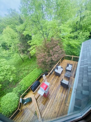 A wooden deck with outdoor furniture, surrounded by lush greenery and trees. - 10,000 Sq. Ft. Home on 15 hunting acres with an in-door pool and sauna (Burlington)