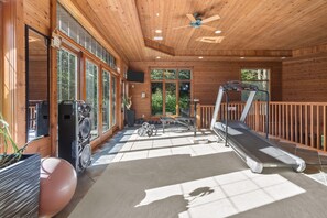Un gimnasio con cintas de correr, pesas y un ventilador de techo.