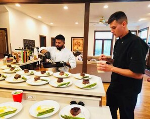 A chef preparing food in a kitchen with a dining area visible in the background. - 10,000 Sq. Ft. Home on 15 hunting acres with an in-door pool and sauna (Burlington)