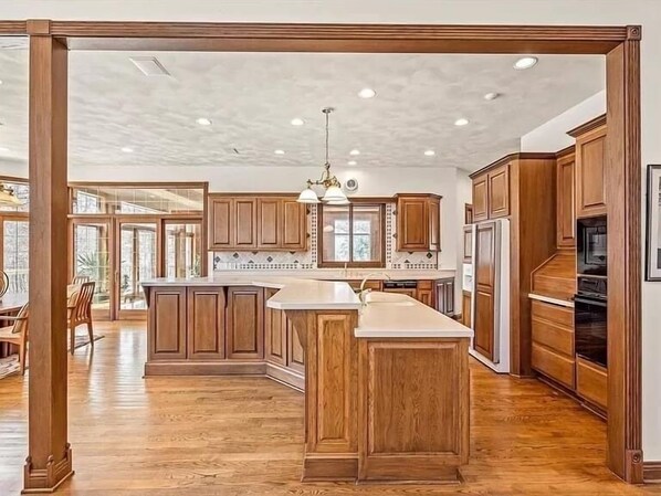 A spacious kitchen with wooden cabinets, a central island, and a large window providing natural light. - 10,000 Sq. Ft. Home on 15 hunting acres with an in-door pool and sauna (Burlington)