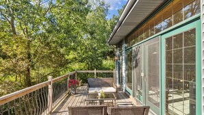 En overdækket terrasse med fletmøbler, et bord og et gelænder.