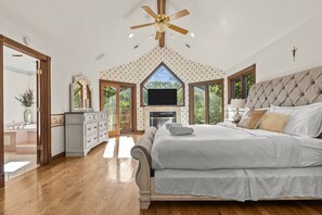 Un dormitorio con una cama grande, televisión y chimenea.