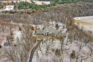 A large, detached house with a symmetrical roof and multiple chimneys, surrounded by a snowy landscape and sparse trees. - 10,000 Sq. Ft. Home on 15 hunting acres with an in-door pool and sauna (Burlington)