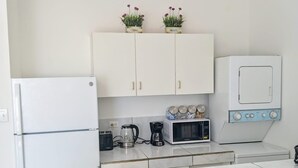 A compact kitchen with white cabinets, a refrigerator, a microwave, a coffee maker, and a kettle. - Cozy, Cole Bay, one bedroom with security and free parking (Cole Bay)