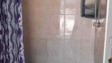 Un baño con ducha, inodoro y un perchero para toallas.