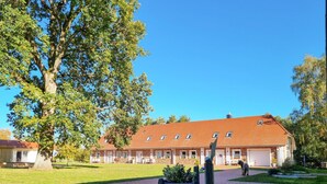 A two-story building with a red-tiled roof, multiple windows, and a paved driveway. - Pet friendly apartment in Passow OT Charlottenho (Passow OT Charlottenho)