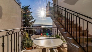 A balcony with a table and chairs, a staircase, and a view of the sea. - 2 bedroom cozy apartment in Crikvenica (Crikvenica)