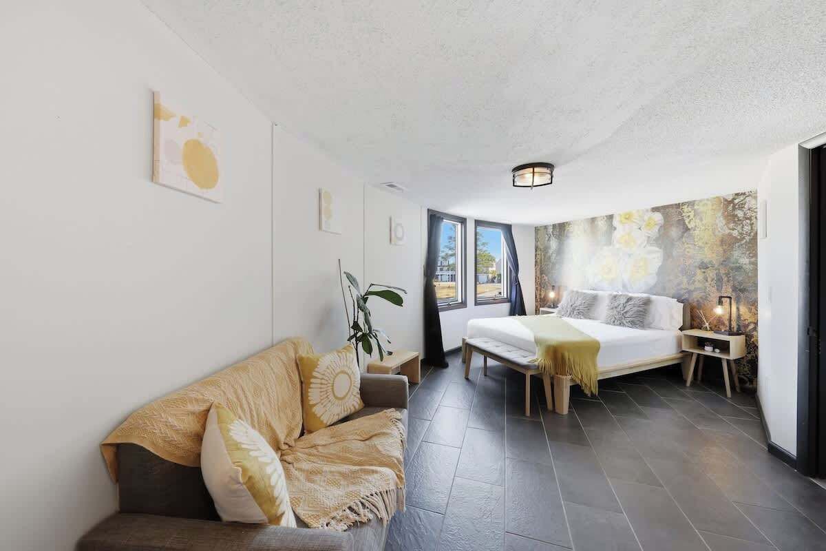 Um quarto moderno com uma cama, um sofá, uma mesinha e uma parede com um mural floral.