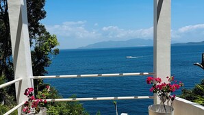 A balcony with a view of the sea, white railings, and two potted plants with flowers. - Picturesque private villa with infinity pool (Puerto Galera)