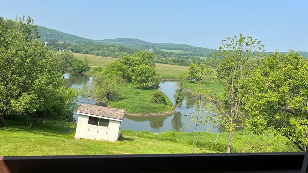 A view of a river with a small building near the water, surrounded by greenery and hills. - Winding River - Panoramic view of river valley, under 10 minutes to Dreams Park (Cooperstown)