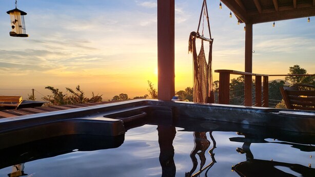 A serene outdoor pool area with a hammock and hanging light fixtures, reflecting the sunset. - Scenic Getaway - Rustic Cabin - Mountain Ridge (Pinon Hills)