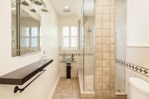 A modern bathroom with a glass shower enclosure, a glass sink, and a dark countertop.