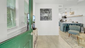 Una cocina moderna con una isla central, un comedor con una silla azul y una puerta verde.