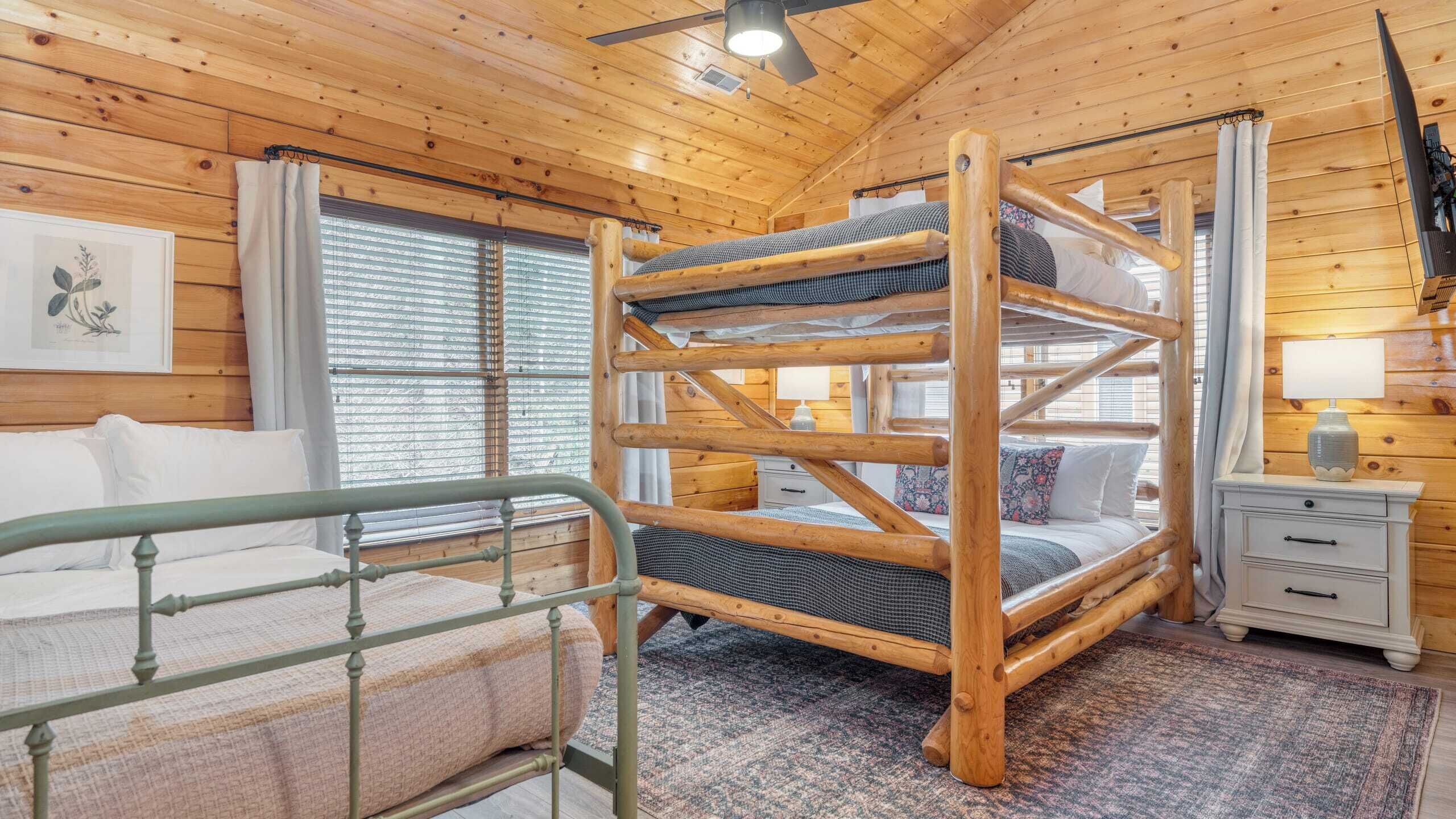 A bunk bed with a metal guardrail, a bedside table with a lamp, and a window with blinds.