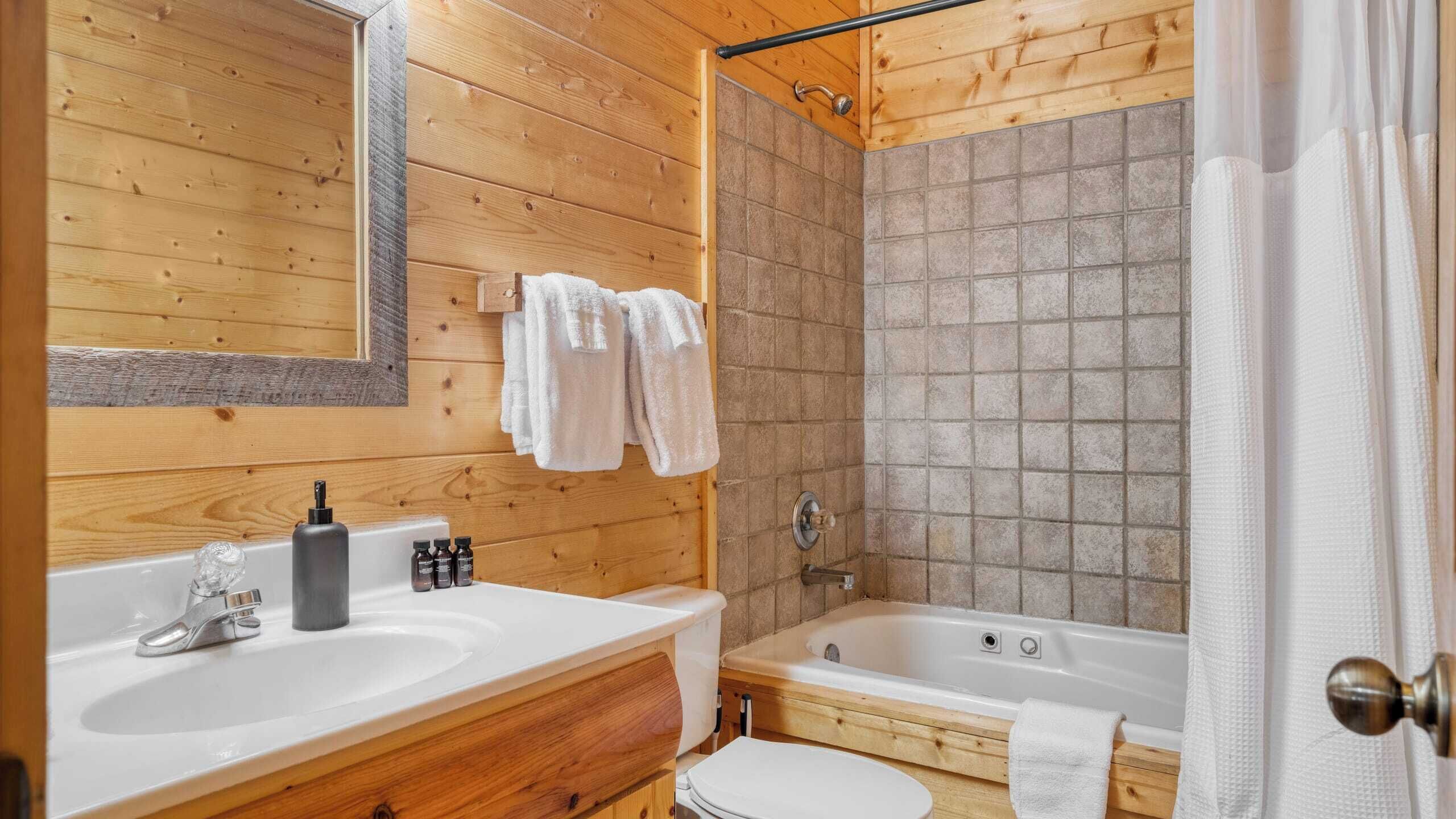 Ein Badezimmer in einer Holzhütte mit einem Doppelwaschbecken, einer Badewanne und einer Dusche.