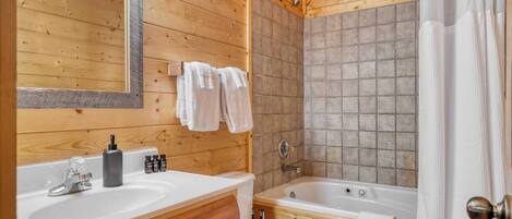 Ein Badezimmer in einer Holzhütte mit einem Doppelwaschbecken, einer Badewanne und einer Dusche.